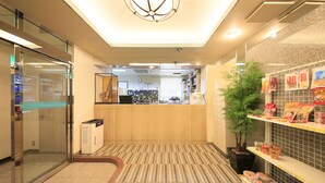 A hotel lobby with a reception desk, a glass elevator, a plant, and a snack bar. - UENO STATION HOSTEL ORIENTAL 2 - Cater to Men (Tokyo)