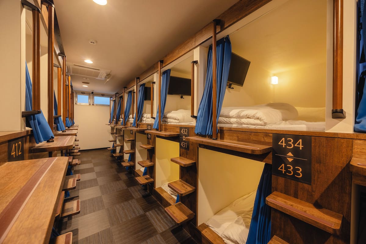 A row of wooden bunk beds with numbers 432 and 433, a checkered floor, and a window in the background.