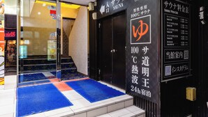 A hotel entrance with a glass door, a blue and red mat, and a black wall with Japanese text. - UENO STATION HOSTEL ORIENTAL 2 - Cater to Men (Tokyo)