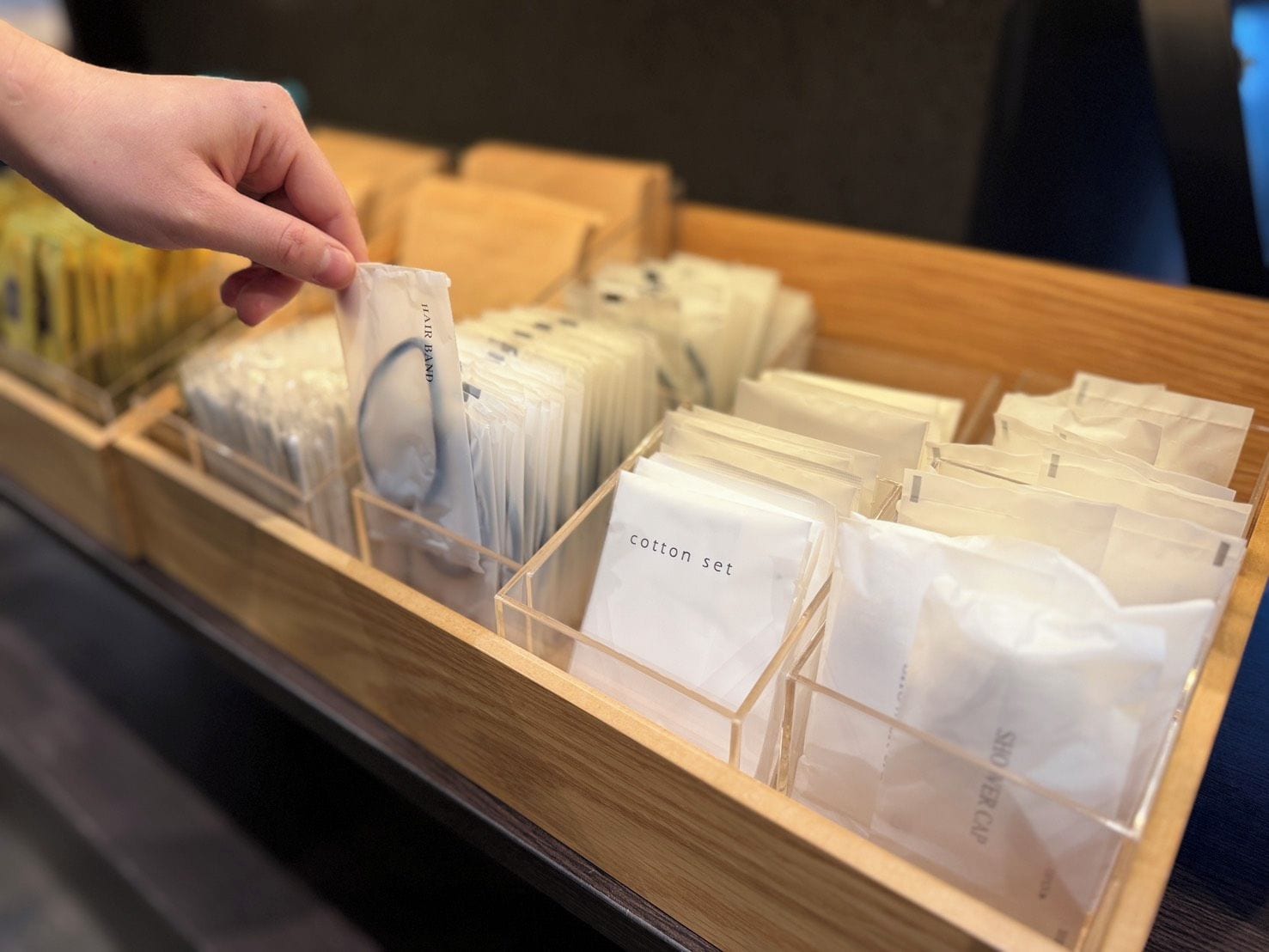 Une vitrine en bois, dotée de plusieurs compartiments, contient des sachets en papier blanc sur lesquels figurent différents noms et titres.