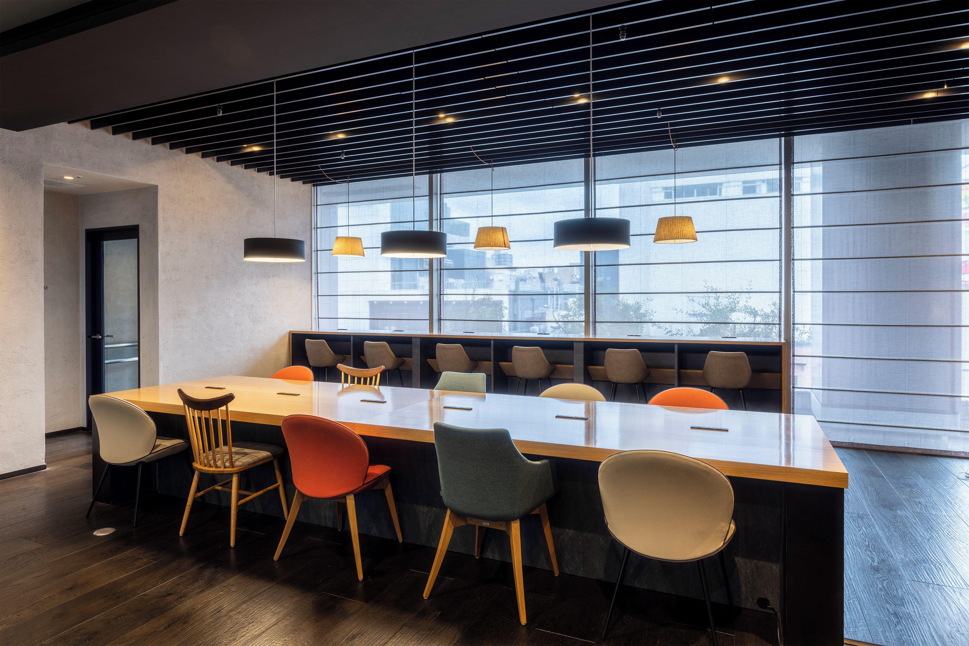 A modern conference room with a long table, multiple chairs, and pendant lighting.