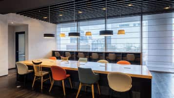 A modern conference room with a long table, multiple chairs, and pendant lighting.