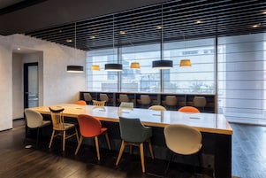 Sala de conferências moderna com uma mesa comprida, várias cadeiras e iluminação pendente.
