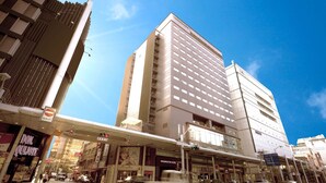 A modern hotel with a prominent entrance, a large sign for the Washington Hotel, and a pedestrian crossing. - Hiroshima Washington Hotel (Hiroshima)