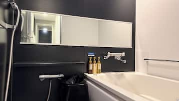 Uma casa de banho moderna com banheira, espelho, porta-toalhas e um cesto de lixo.