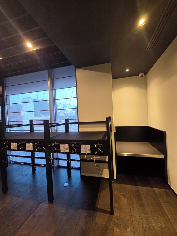 A room with a bunk bed, a table with electrical outlets, and a window with a view of buildings. - Hiroshima Washington Hotel (Hiroshima)