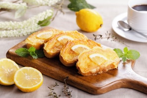 A wooden board with lemon slices and mint leaves, a whole lemon, and a cup of coffee on a table. - Hiroshima Washington Hotel (Hiroshima)