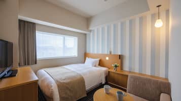 A hotel room with a bed, a desk, a chair, a small table, and a window with curtains.
