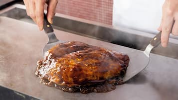 A person using a spatula to serve a glazed meat dish on a flat surface.