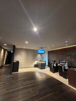 Eine moderne Lobby mit einer Rezeption, einem Wandfernseher und Self-Service-Terminals.