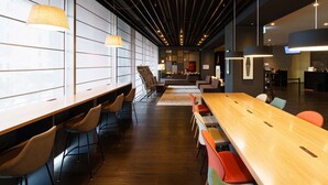 Een moderne vergaderruimte met lange tafels, stoelen en een groot scherm.
