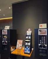 Zona de venta de café con dos máquinas, una para descafeinado y otra para café regular, y una exhibición de vasos desechables.