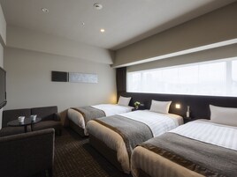 Una habitación de hotel con dos camas, un sofá, una pequeña mesa y un televisor.