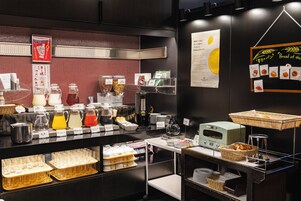 Una barra de desayuno con diversas opciones de comida y bebida, incluyendo café y té.