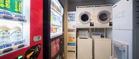 A laundromat with vending machines, a washing machine, and a dryer.