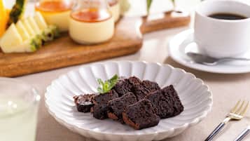 A plate of brownies on a white plate with a fork and spoon beside it.