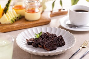 Un plato de brownies sobre un plato blanco, con un tenedor y una cuchara al lado.