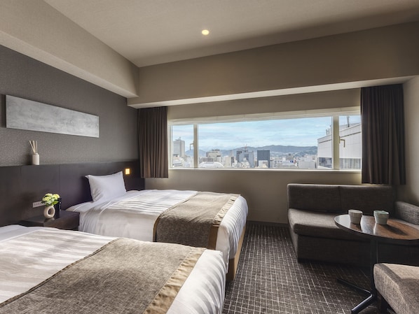 A hotel room with two beds, a view of the cityscape, a small table, and a chair. - Hiroshima Washington Hotel (Hiroshima)