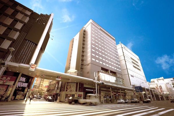 Un edificio de varios pisos con un llamativo letrero que dice 'Washington Hotel', un paso elevado para peatones y un cruce de calles.