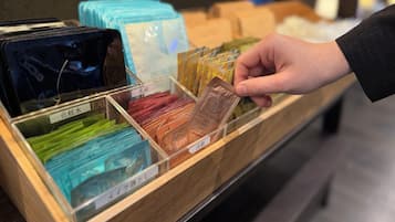 A hand selecting a face wash product from a wooden display case containing various skincare items.