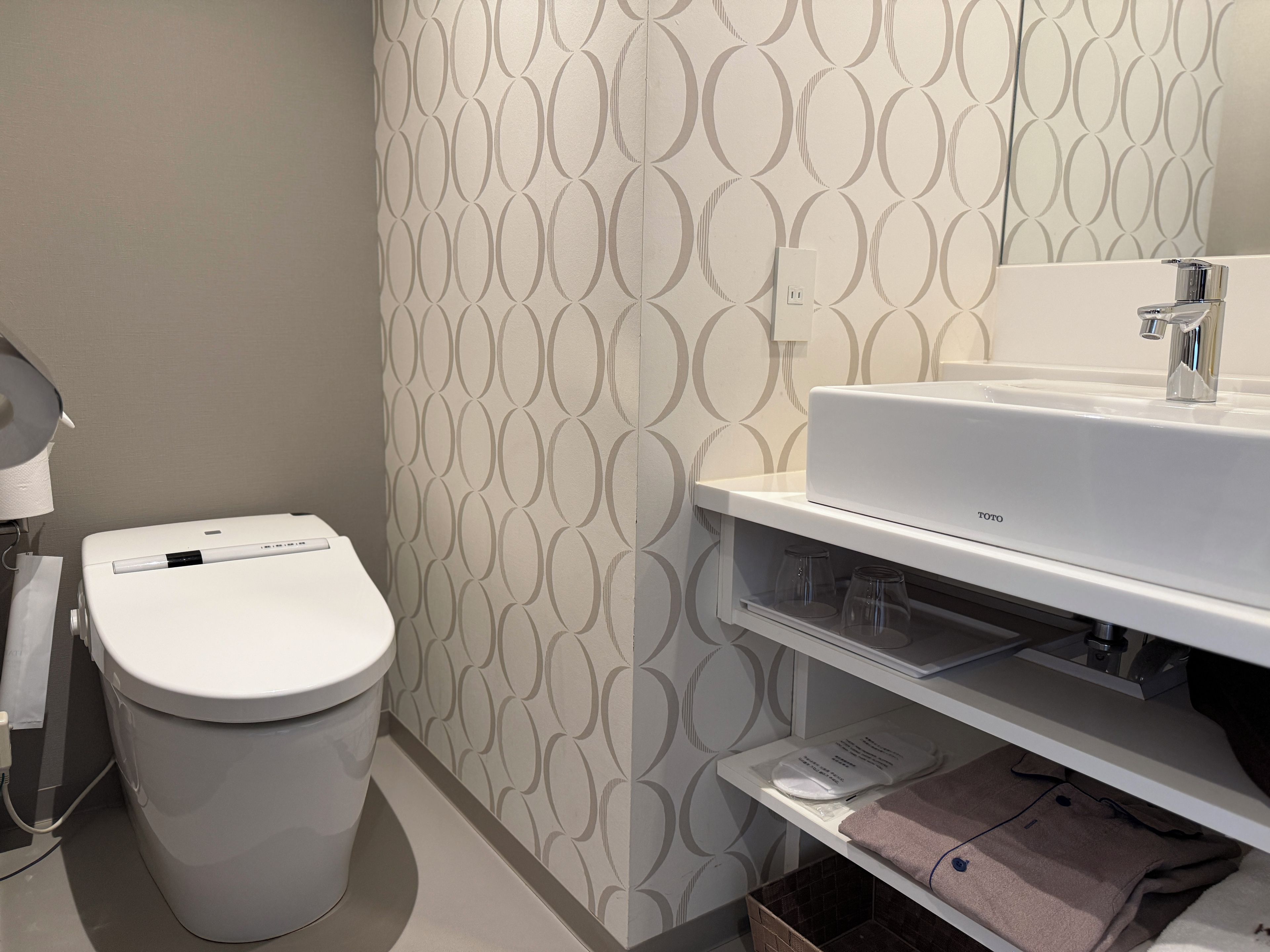 Un baño con inodoro, lavamanos y pared con diseño.