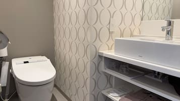 A bathroom with a toilet, a sink, and a patterned wall.