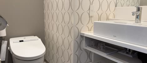 Un baño con inodoro, lavamanos y pared con diseño.