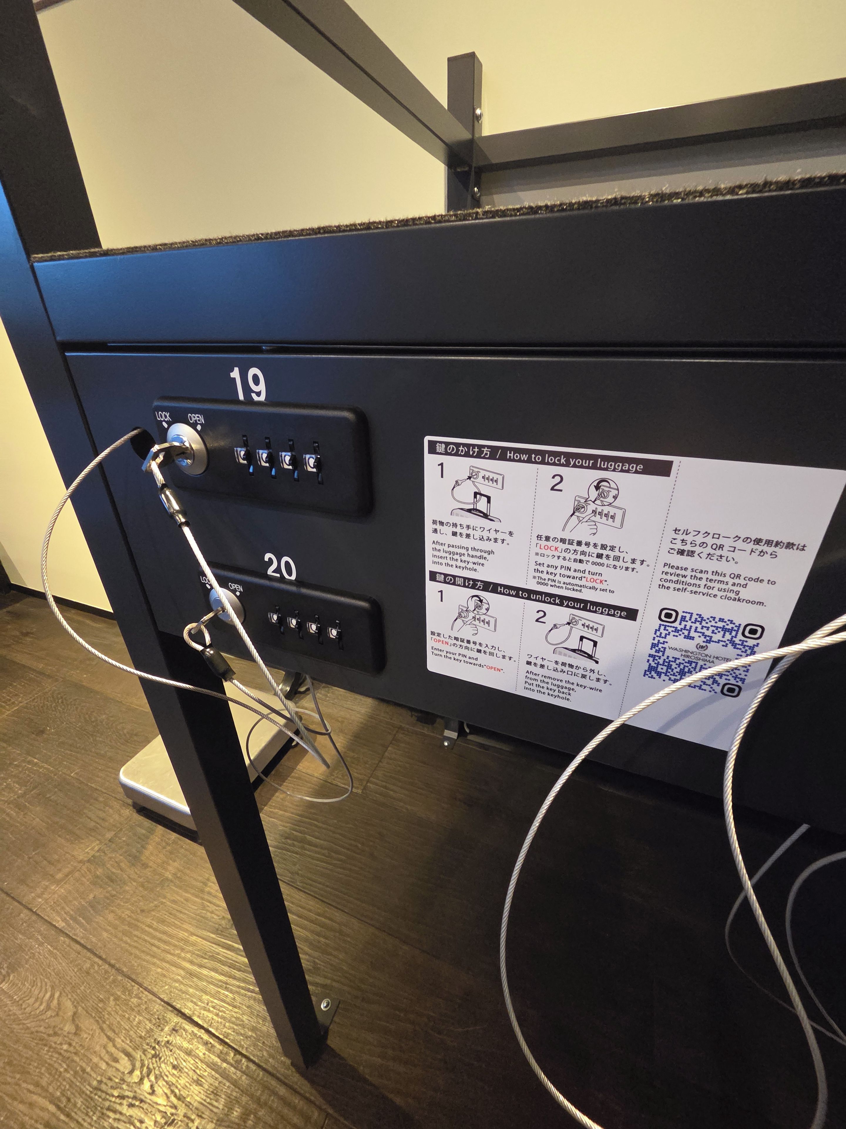 A luggage storage area with numbered slots 19 and 20, a QR code, and a cable connected to a lock mechanism.