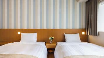 A hotel room with two beds, a wooden headboard, a striped wall, and a small table with a vase of flowers.