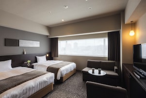Habitación de hotel con dos camas, un sofá, un televisor y una ventana con cortinas.