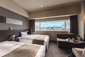 A hotel room with two beds, a sofa, a small table, and a view of the city. - Hiroshima Washington Hotel (Hiroshima)