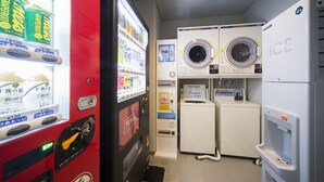 A laundromat with a red vending machine, two washing machines, and a dryer. - Hiroshima Washington Hotel (Hiroshima)