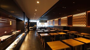 A restaurant interior with wooden tables and chairs, a long counter with stacked plates, and decorative wall panels. - Hiroshima Washington Hotel (Hiroshima)