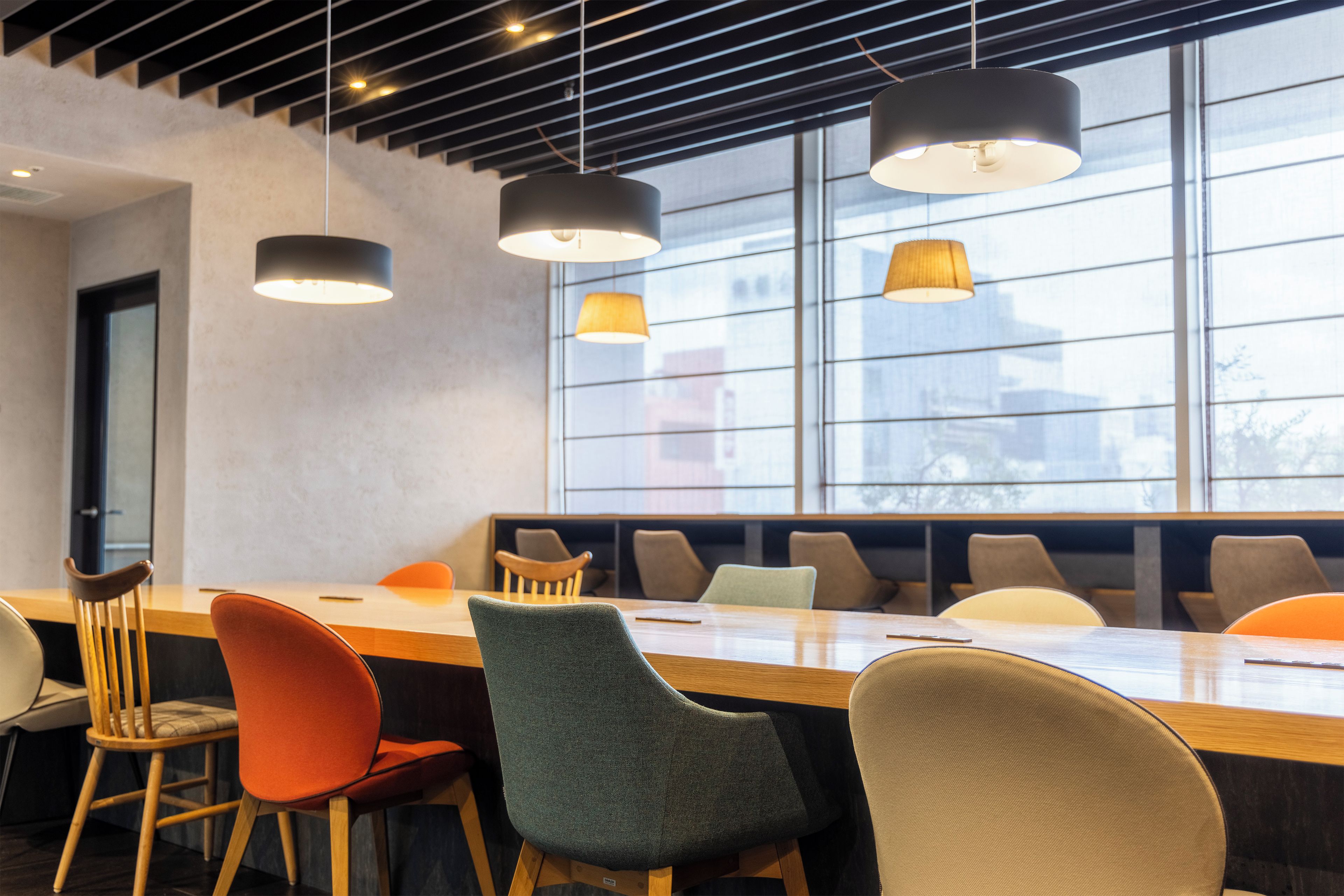 A conference room with a long table, multiple chairs, and pendant lighting.
