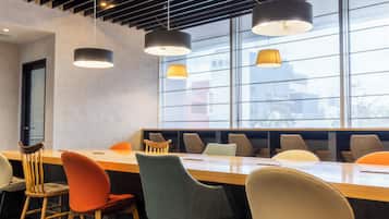 A conference room with a long table, multiple chairs, and pendant lighting.