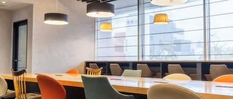 A conference room with a long table, multiple chairs, and pendant lighting.