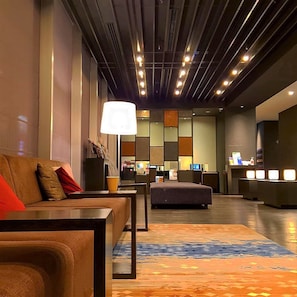 A hotel lobby with a sofa, ottoman, and a reception desk. - Hiroshima Washington Hotel (Hiroshima)