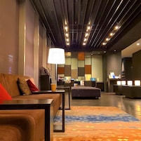 Eine Hotelhalle mit einer Couch, einem Hocker und einer Rezeption.