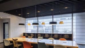 A modern conference room with a long table, multiple chairs, and a large window with a view of buildings. - Hiroshima Washington Hotel (Hiroshima)