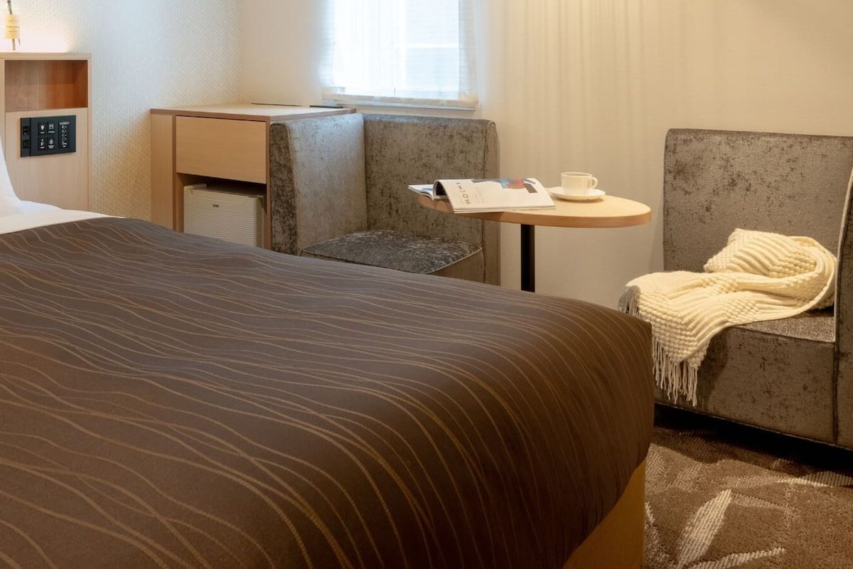 Una habitación de hotel con una cama grande, una mesita con una silla y un sofá.