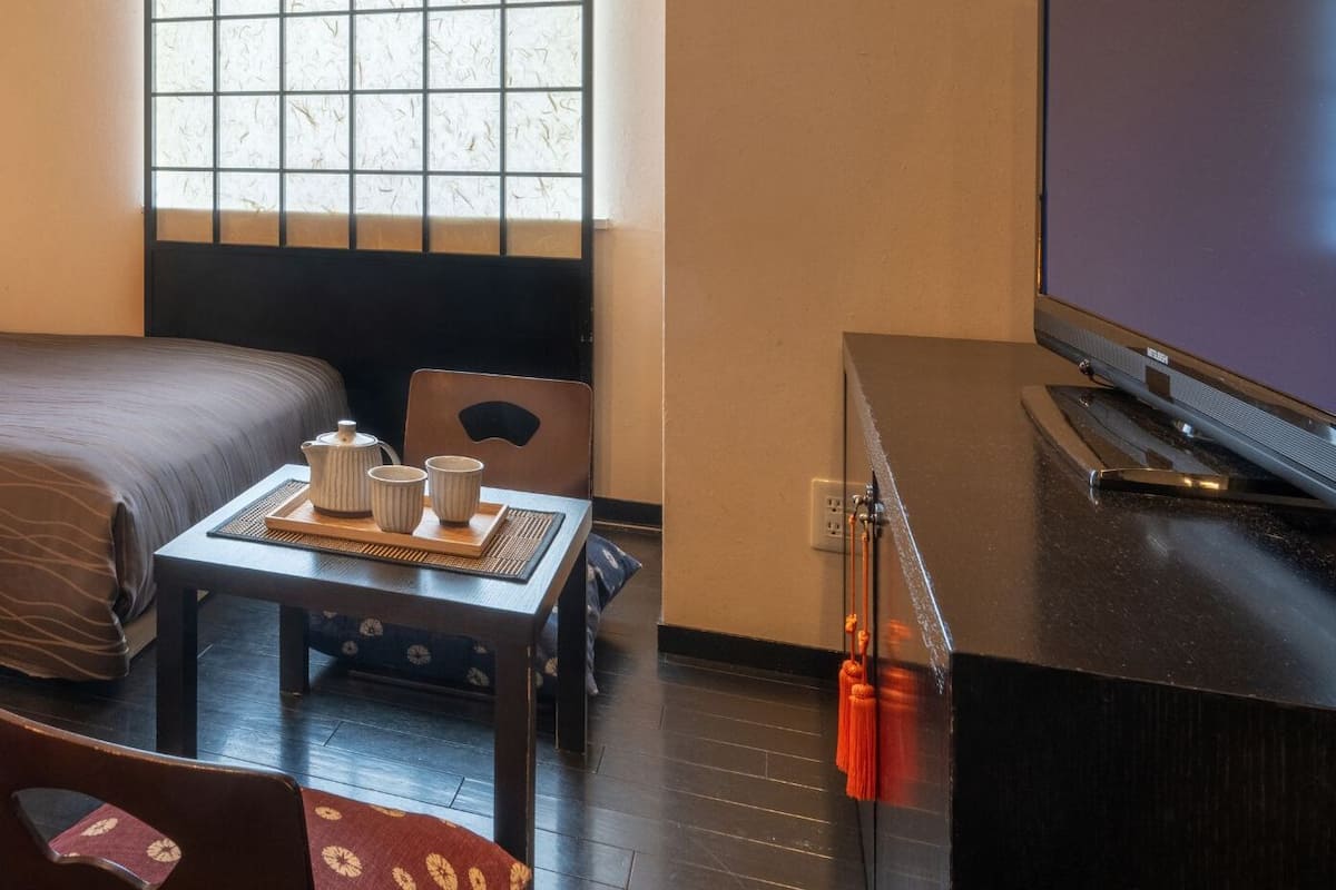 Habitación de hotel con dos camas, un escritorio con televisor y una ventana con vistas.