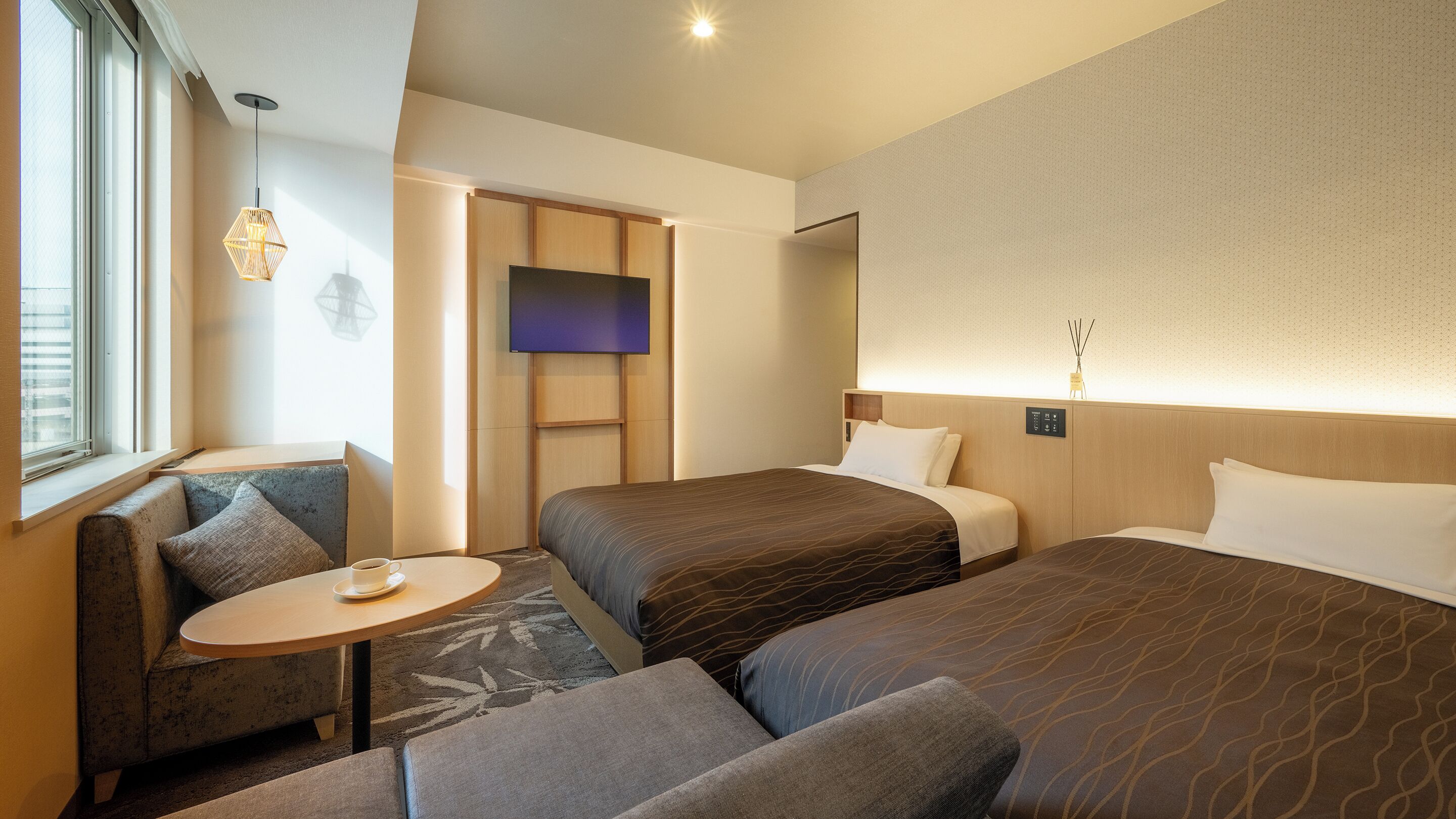 A hotel room with two beds, a small table, and a seating area.
