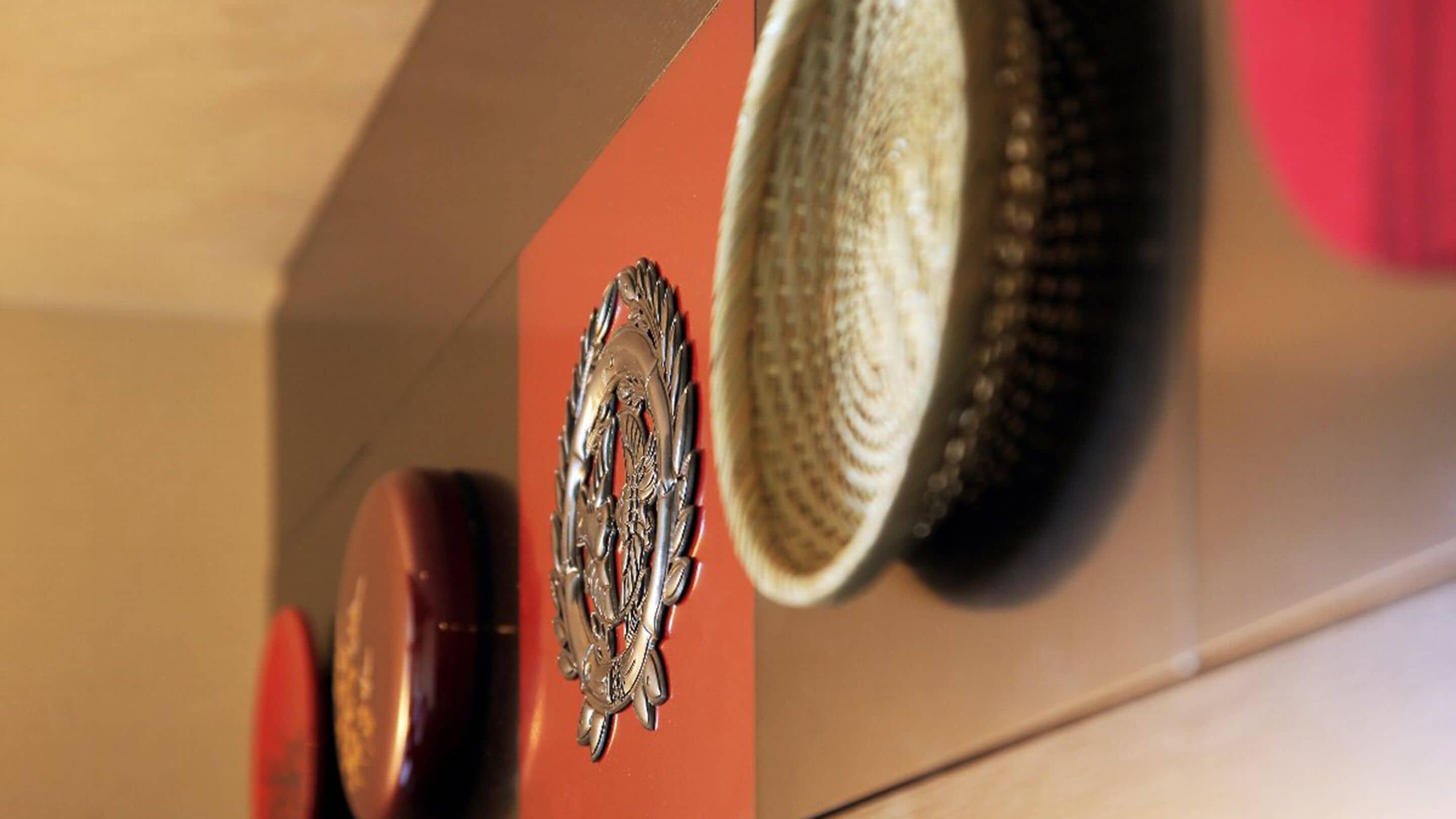 A close-up of a wall with a decorative metal emblem and a woven basket.