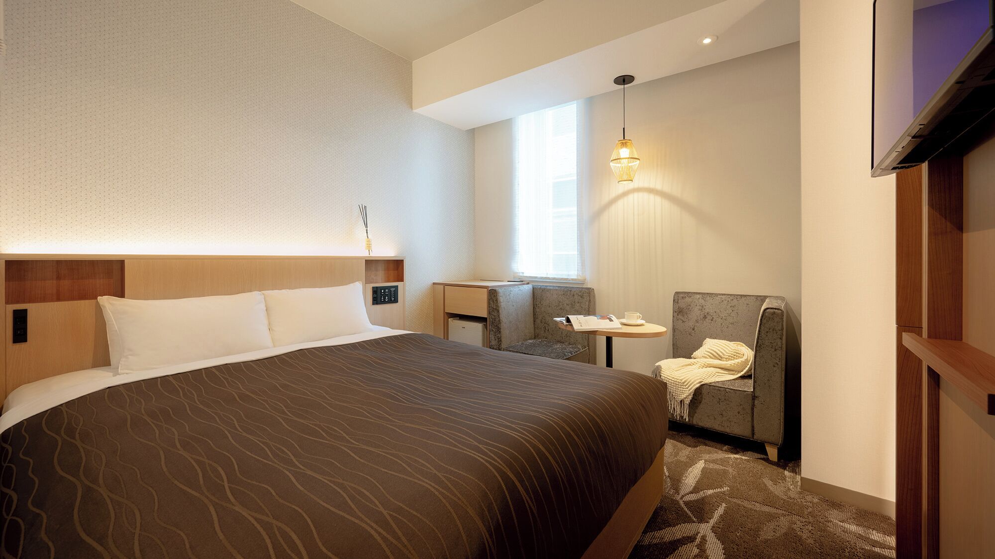 Een hotelkamer met een groot bed, een bureau, een stoel, een televisie en een raam.