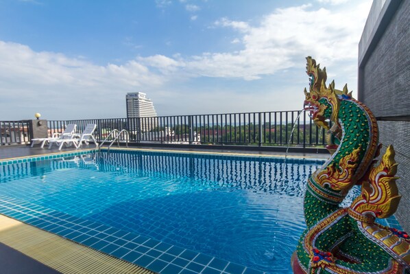 A rooftop pool with a decorative dragon sculpture, lounge chairs, and a view of a cityscape. - Baan Nilrath Hotel (Hua Hin)