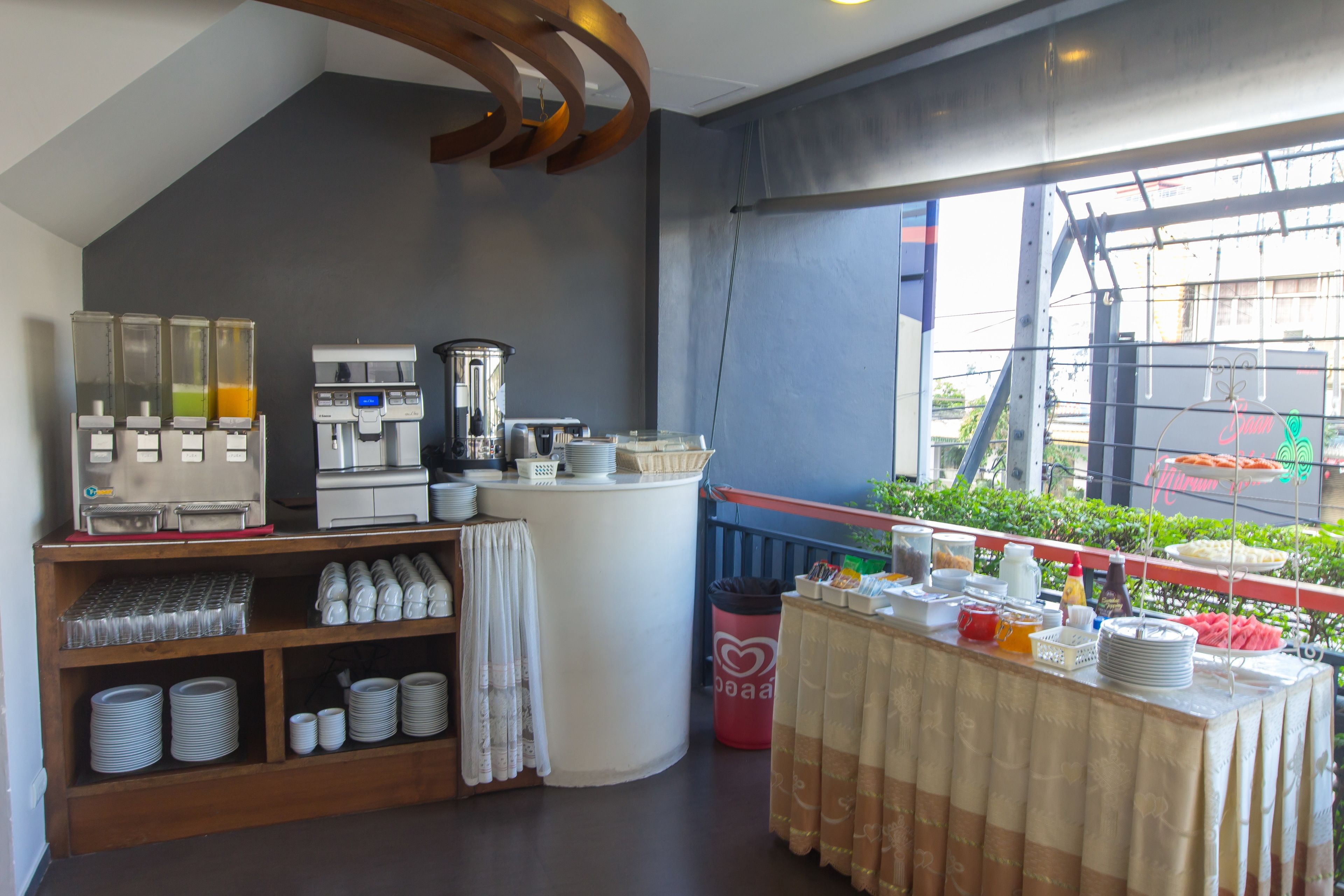 A modern kitchen with a coffee machine, a blender, and a buffet setup with plates and bowls.