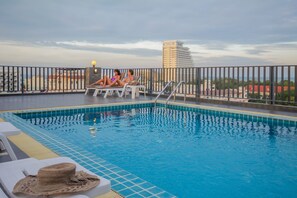 A rooftop pool with lounge chairs and a view of a cityscape. - Baan Nilrath Hotel (Hua Hin)