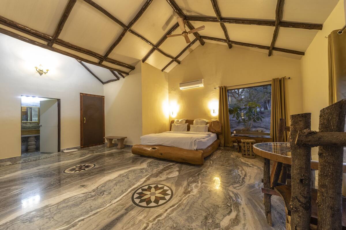 A spacious bedroom with a large bed, a wooden headboard, and a marble floor with geometric patterns.