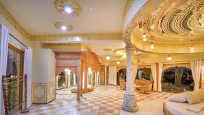 A luxurious hotel lobby with ornate columns, checkered flooring, and a seating area with a sofa and chairs. - Lohagarh Fort Resort (Amer)