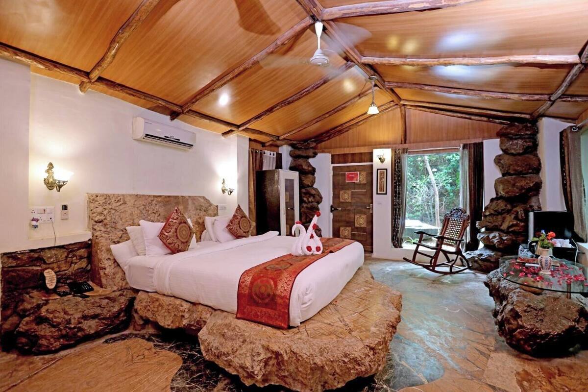 A room with a bed, a rocking chair, and a stone wall.